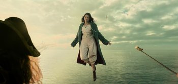 Movie still from “Peter Pan & Wendy” (2023), directed by David Lowery – A woman is jumping in the air over a body of water; Wide shot, Low angle