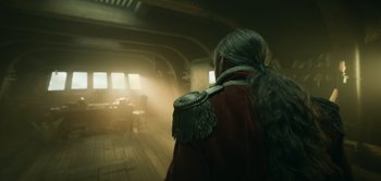 Movie still from “Peter Pan & Wendy” (2023), directed by David Lowery – A man in a red jacket is standing in a room; Medium shot, Over the shoulder angle