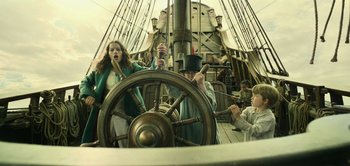 Movie still from “Peter Pan & Wendy” (2023), directed by David Lowery – A group of people sitting on a boat steering it; Medium shot, Low angle