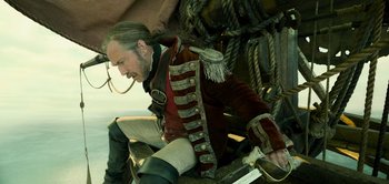 Movie still from “Peter Pan & Wendy” (2023), directed by David Lowery – A man sitting on the ground wearing a red jacket; Medium shot, Low angle