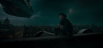 Movie still from “Peter Pan & Wendy” (2023), directed by David Lowery – A man sitting on top of a building at night; Wide shot, High angle