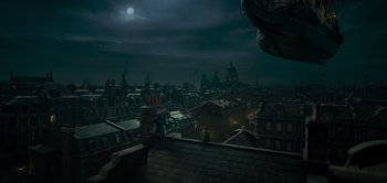 Movie still from “Peter Pan & Wendy” (2023), directed by David Lowery – A view of a city at night with a full moon in the background; Extreme Wide shot, High angle