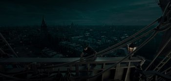 Movie still from “Peter Pan & Wendy” (2023), directed by David Lowery – A man standing on a railing looking over a city at night; Extreme Wide shot, High angle