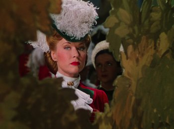 Movie still from “Phantom of the Opera” (1943), directed by Arthur Lubin – A woman wearing a white hat standing next to another woman in a red dress; Close Up shot, Low angle