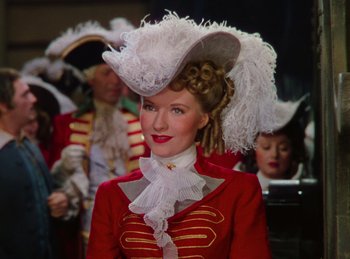 Movie still from “Phantom of the Opera” (1943), directed by Arthur Lubin – A woman in a red and white outfit with a white hat; Medium shot, Low angle