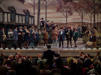 Movie still from “Phantom of the Opera” (1943), directed by Arthur Lubin – A crowd of people standing on a stage with a painting; Extreme Wide shot, High angle