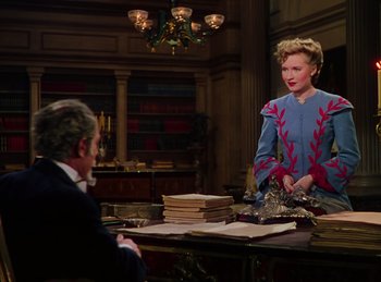 Movie still from “Phantom of the Opera” (1943), directed by Arthur Lubin – An older woman in a blue dress talking to an older man in a blue suit; Medium shot, High angle