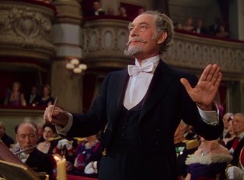 Movie still from “Phantom of the Opera” (1943), directed by Arthur Lubin – An old man in a suit and bow tie holding a conductor's baton; Medium shot, Low angle