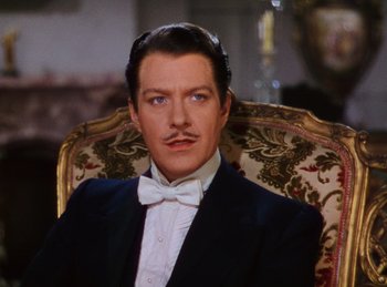 Movie still from “Phantom of the Opera” (1943), directed by Arthur Lubin – A person sitting in a chair wearing a suit; Close Up shot, High angle