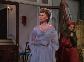 Movie still from “Phantom of the Opera” (1943), directed by Arthur Lubin – A woman in a blue dress standing in front of a mirror; Medium shot, Low angle