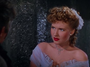 Movie still from “Phantom of the Opera” (1943), directed by Arthur Lubin – A woman in a white dress and a necklace; Close Up shot, Over the shoulder angle