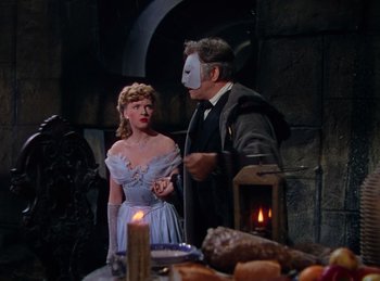 Movie still from “Phantom of the Opera” (1943), directed by Arthur Lubin – A man and a woman wearing masks in front of a fireplace; Medium shot, Over the shoulder angle