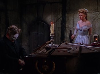 Movie still from “Phantom of the Opera” (1943), directed by Arthur Lubin – A man and a woman standing in front of a table; Medium shot, High angle