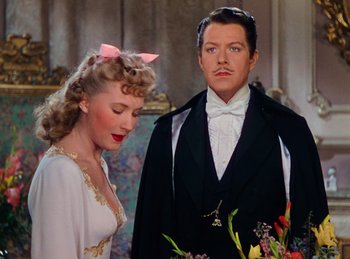 Movie still from “Phantom of the Opera” (1943), directed by Arthur Lubin – A man and a woman standing next to each other; Medium shot, Over the shoulder angle