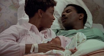 Movie still from “Philadelphia” (1993), directed by Jonathan Demme – A man and a woman holding a baby in a hospital bed; Close Up shot, High angle