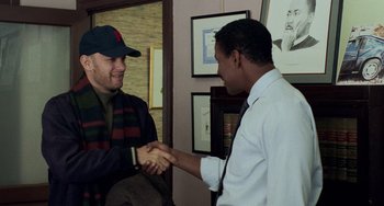 Movie still from “Philadelphia” (1993), directed by Jonathan Demme – Two men shaking hands in a room with pictures on the wall; Medium shot, Over the shoulder angle