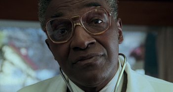 Movie still from “Philadelphia” (1993), directed by Jonathan Demme – An older man wearing glasses with a stethoscope around his neck; Close Up shot, Low angle