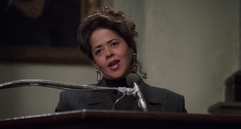 Movie still from “Philadelphia” (1993), directed by Jonathan Demme – A woman is speaking at a podium in front of microphones; Close Up shot, Low angle
