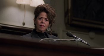 Movie still from “Philadelphia” (1993), directed by Jonathan Demme – A woman in a black jacket is sitting in front of a microphone; Close Up shot, Low angle
