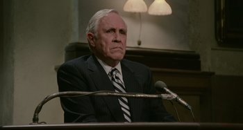 Movie still from “Philadelphia” (1993), directed by Jonathan Demme – An older man in a suit sitting in front of microphones; Close Up shot, Over the shoulder angle