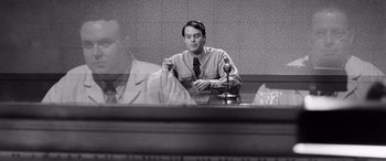 Movie still from “Pineapple Express” (2008), directed by David Gordon Green – A black and white photo of a man sitting at a table; Medium shot, Over the shoulder angle