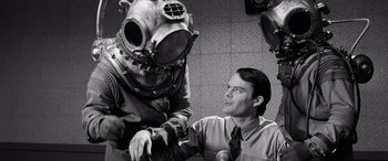 Movie still from “Pineapple Express” (2008), directed by David Gordon Green – A man in a suit and tie next to a man in a diving helmet; Medium shot, High angle