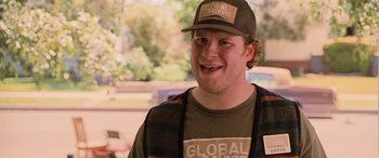 Movie still from “Pineapple Express” (2008), directed by David Gordon Green – A young man wearing a hat and smiling for the camera; Close Up shot, Over the shoulder angle