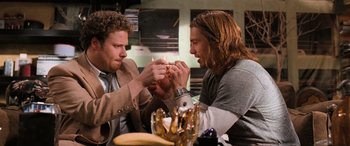 Movie still from “Pineapple Express” (2008), directed by David Gordon Green – Two men sitting at a table with a lit candle in their hands; Medium shot, Overhead angle