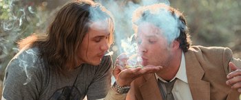 Movie still from “Pineapple Express” (2008), directed by David Gordon Green – Two young men are smoking marijuana and one of them is smoking a cigarette; Close Up shot, Low angle
