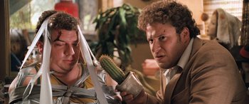 Movie still from “Pineapple Express” (2008), directed by David Gordon Green – Two men holding a knife and a potted cactus; Medium shot, Low angle