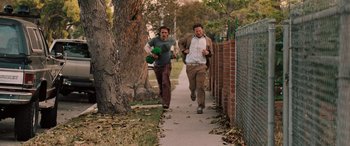 Movie still from “Pineapple Express” (2008), directed by David Gordon Green – Two men running down a sidewalk near a brick wall; Wide shot, High angle