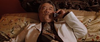 Movie still from “Pineapple Express” (2008), directed by David Gordon Green – An older man wearing a suit and tie while talking on a cell phone; Medium shot, Low angle