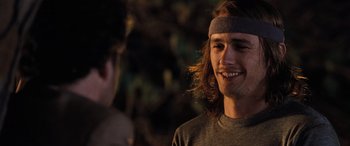 Movie still from “Pineapple Express” (2008), directed by David Gordon Green – A man with long hair wearing a headband and smiling; Close Up shot, Over the shoulder angle
