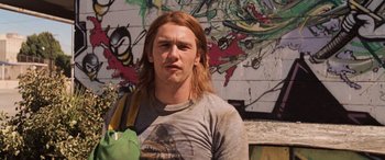 Movie still from “Pineapple Express” (2008), directed by David Gordon Green – A man with long red hair is standing in front of a graffiti wall; Close Up shot, Low angle