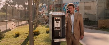 Movie still from “Pineapple Express” (2008), directed by David Gordon Green – A man talking on a phone next to an old payphone; Medium shot, High angle