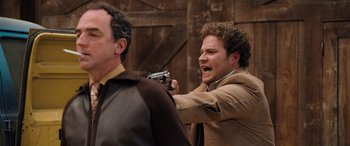 Movie still from “Pineapple Express” (2008), directed by David Gordon Green – A man holding a gun up to his face; Medium shot, Over the shoulder angle