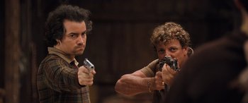 Movie still from “Pineapple Express” (2008), directed by David Gordon Green – A man and a woman holding guns in a room; Medium shot, Low angle