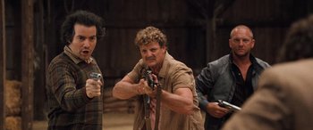 Movie still from “Pineapple Express” (2008), directed by David Gordon Green – A man holding a gun while standing next to another man; Medium shot, Low angle