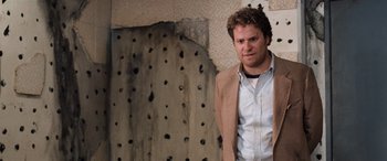 Movie still from “Pineapple Express” (2008), directed by David Gordon Green – A man standing in front of a hole in the wall; Medium shot, Over the shoulder angle