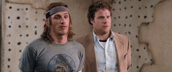 Movie still from “Pineapple Express” (2008), directed by David Gordon Green – Two men standing next to each other in front of a wall; Medium shot, Low angle