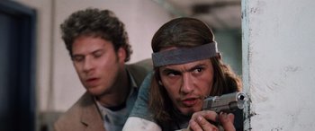 Movie still from “Pineapple Express” (2008), directed by David Gordon Green – A man holding a gun in front of another man; Close Up shot, Low angle