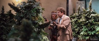 Movie still from “Pineapple Express” (2008), directed by David Gordon Green – A couple of men standing next to each other near a plant; Medium shot, High angle