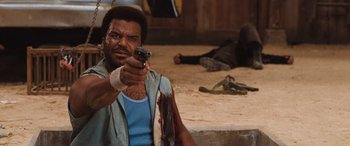 Movie still from “Pineapple Express” (2008), directed by David Gordon Green – A man holding a gun while sitting on the ground; Close Up shot, Over the shoulder angle