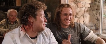 Movie still from “Pineapple Express” (2008), directed by David Gordon Green – Two young men sitting next to each other and smiling; Close Up shot, Low angle