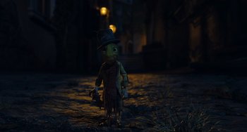Movie still from “Pinocchio” (2022), directed by Robert Zemeckis – A toy doll wearing a top hat and holding a bag; Medium shot, Over the shoulder angle