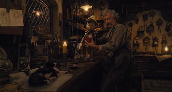 Movie still from “Pinocchio” (2022), directed by Robert Zemeckis – An old man holding a stuffed animal in a room; Wide shot, Low angle