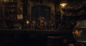 Movie still from “Pinocchio” (2022), directed by Robert Zemeckis – A stuffed animal sitting on top of a wooden table; Wide shot, Low angle