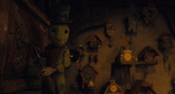Movie still from “Pinocchio” (2022), directed by Robert Zemeckis – A statue of a frog wearing a top hat; Close Up shot, Over the shoulder angle