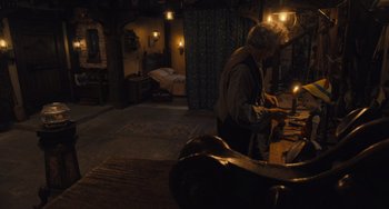 Movie still from “Pinocchio” (2022), directed by Robert Zemeckis – An old man is working in a dimly - lit room; Wide shot, Overhead angle