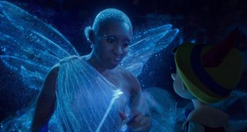 Movie still from “Pinocchio” (2022), directed by Robert Zemeckis – A woman dressed as a fairy is standing next to a boy; Medium shot, Over the shoulder angle